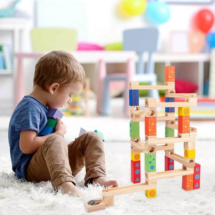 petit garçon de 3 ans qui joue avec le circuit de bille en bois