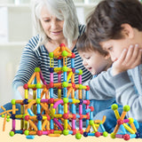 Enfant de 4 ans qui joue avec ses grand-parents dans le salon avec un jeu de construction magnétique et jeu aimanté
