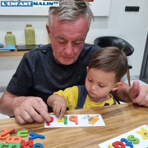 Grand parents qui joue avec son petit fils à un jeu éducatifs pour apprendre l anglais pour les enfants et les débutants des lettres colorés alphabet et des cartes avec des illustrations pour chaque mot pour apprendre l'anglais moment de partage parents enfants avec l enfant malin collection anglais pour enfants