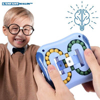 Enfant très souriant qui joue avec son Fidgets toys casse tête anti-stress de couleur bleu pour enfants et adultes